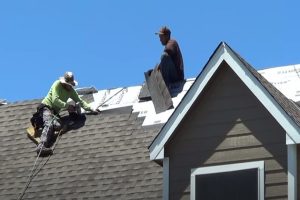 New roof installation by two workers with safety ropes on